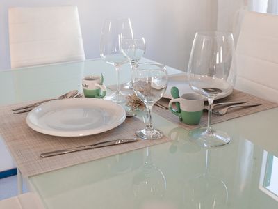 La zona pranzo con tavolo in vetro apparecchiato.