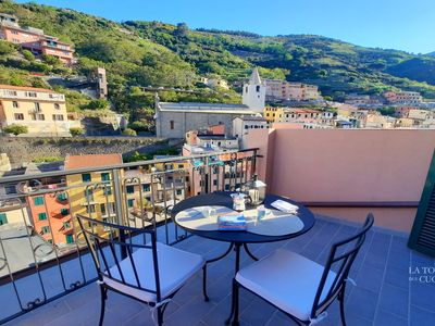 Goditi la tua terrazza privata con vista panoramica sul villaggio, ideale per colazione, caffè o un bicchiere di vino.